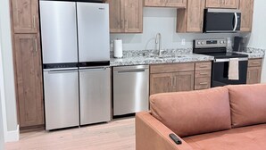 Una cocina moderna con electrodomésticos de acero inoxidable, armarios de madera y un sofá rosa en la zona de estar.