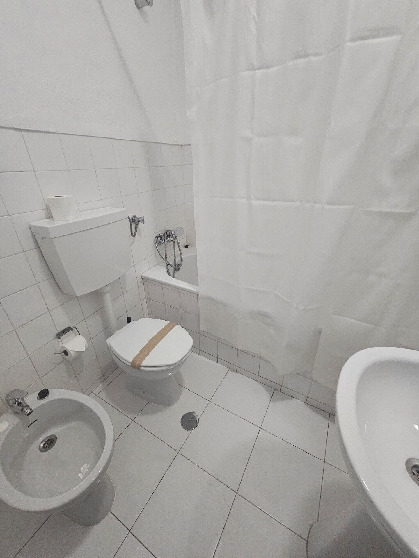 A bathroom with a toilet, bidet, and sink.