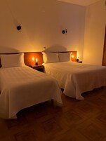 Ein Hotelzimmer mit zwei Einzelbetten, jeweils mit einem Nachttisch und einer Wandlampe.