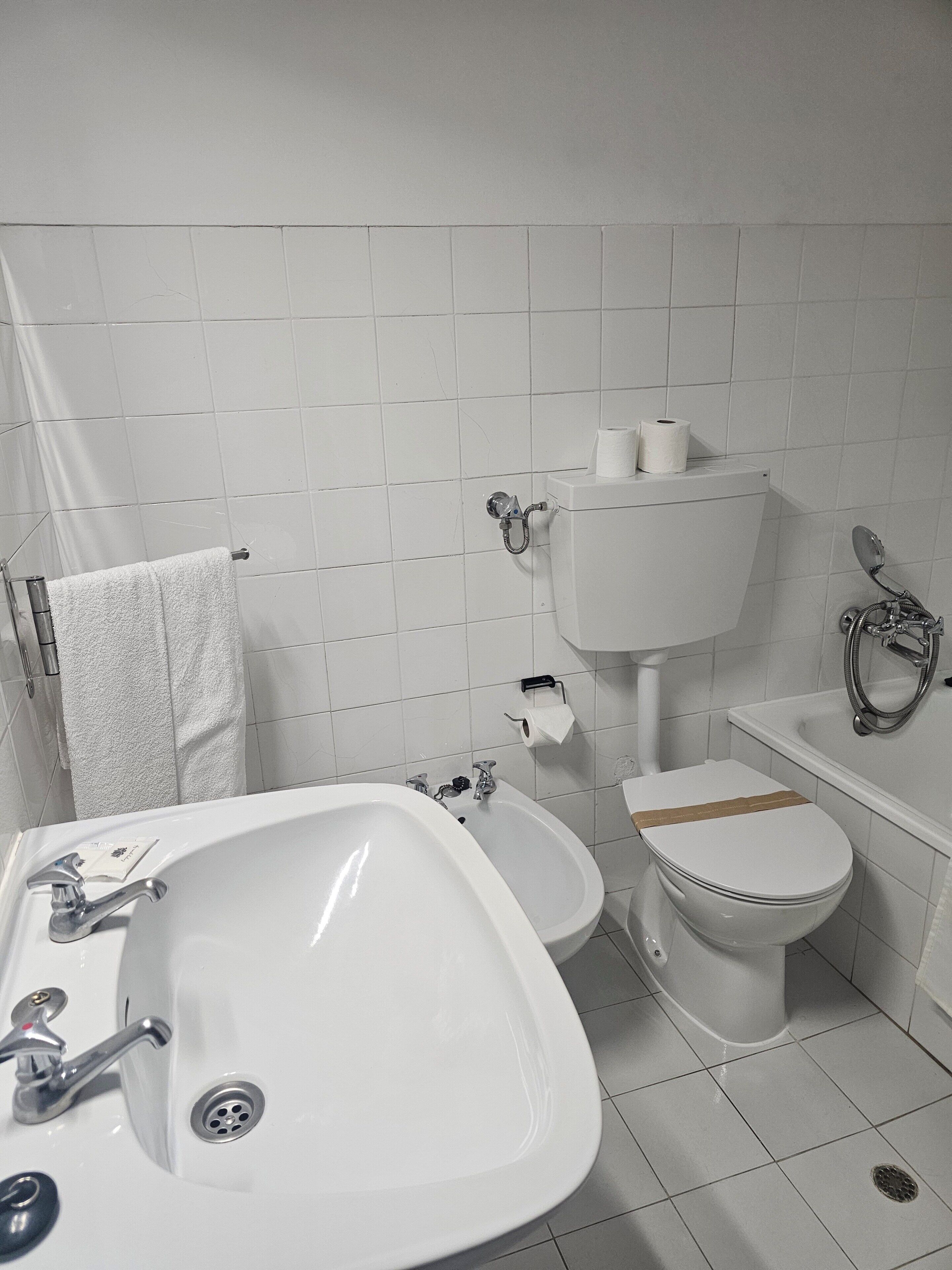Un baño con lavamanos, bidé, inodoro y ducha.