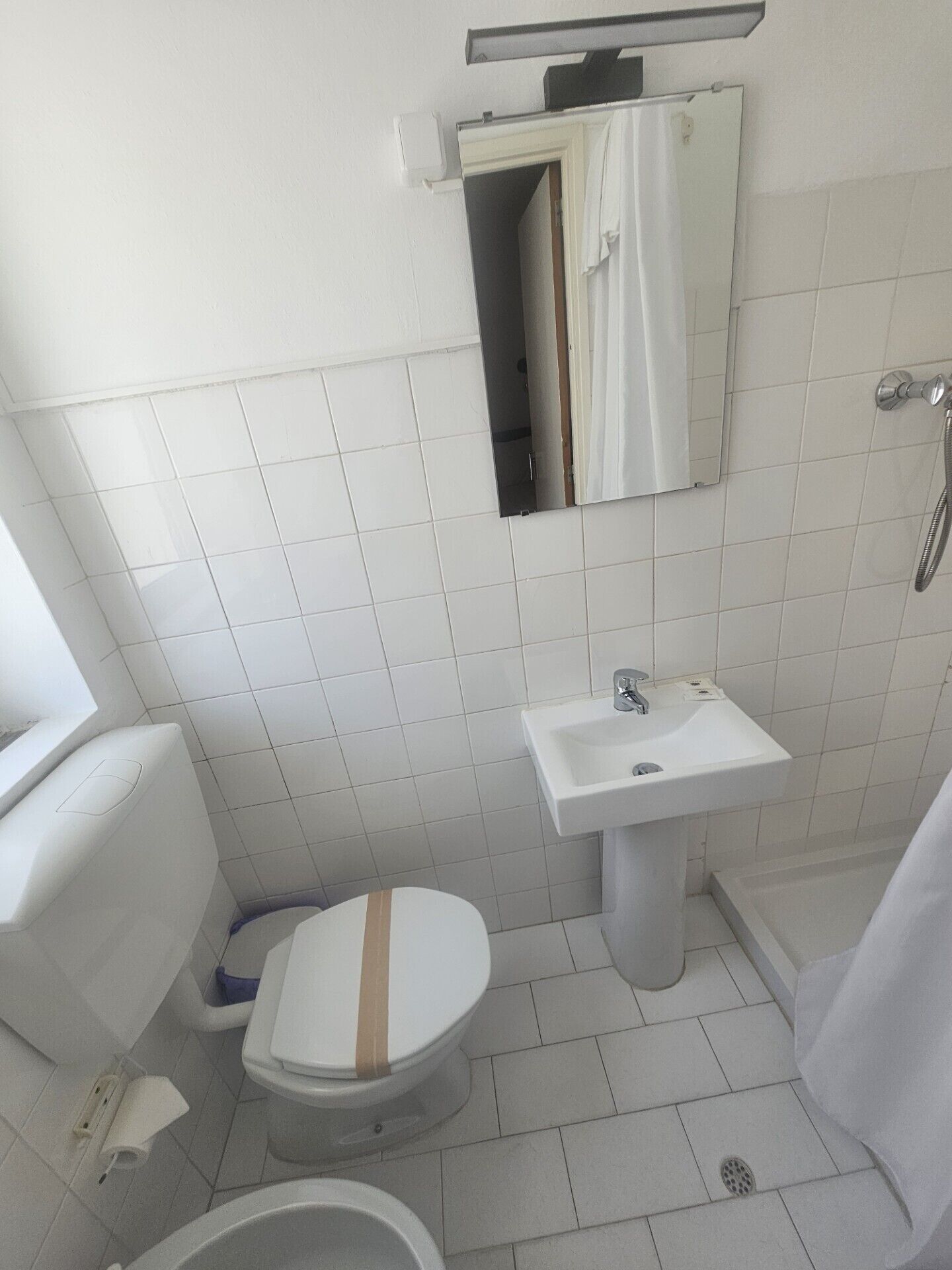 A bathroom with a toilet, sink, and shower.