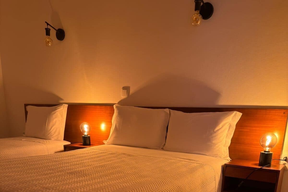 A neatly made bed with a textured blanket, two bedside tables with wall-mounted lamps, and a wooden headboard.