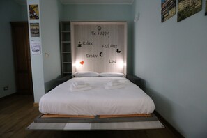 A bed with a white mattress and pillows, a wooden headboard with motivational words, and a small shelf above the bed. - Casa Hexa – Smart studio with balcony, AC & free parking (Torino)