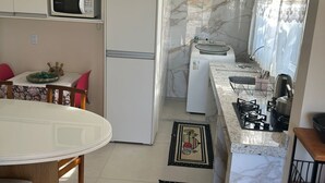 Una cocina compacta equipada con microondas, refrigerador, estufa y un comedor con mesa y sillas.