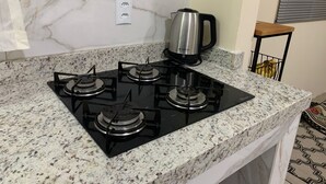Una cocina con estufa a gas de cuatro quemadores, cafetera y un enchufe en la pared.