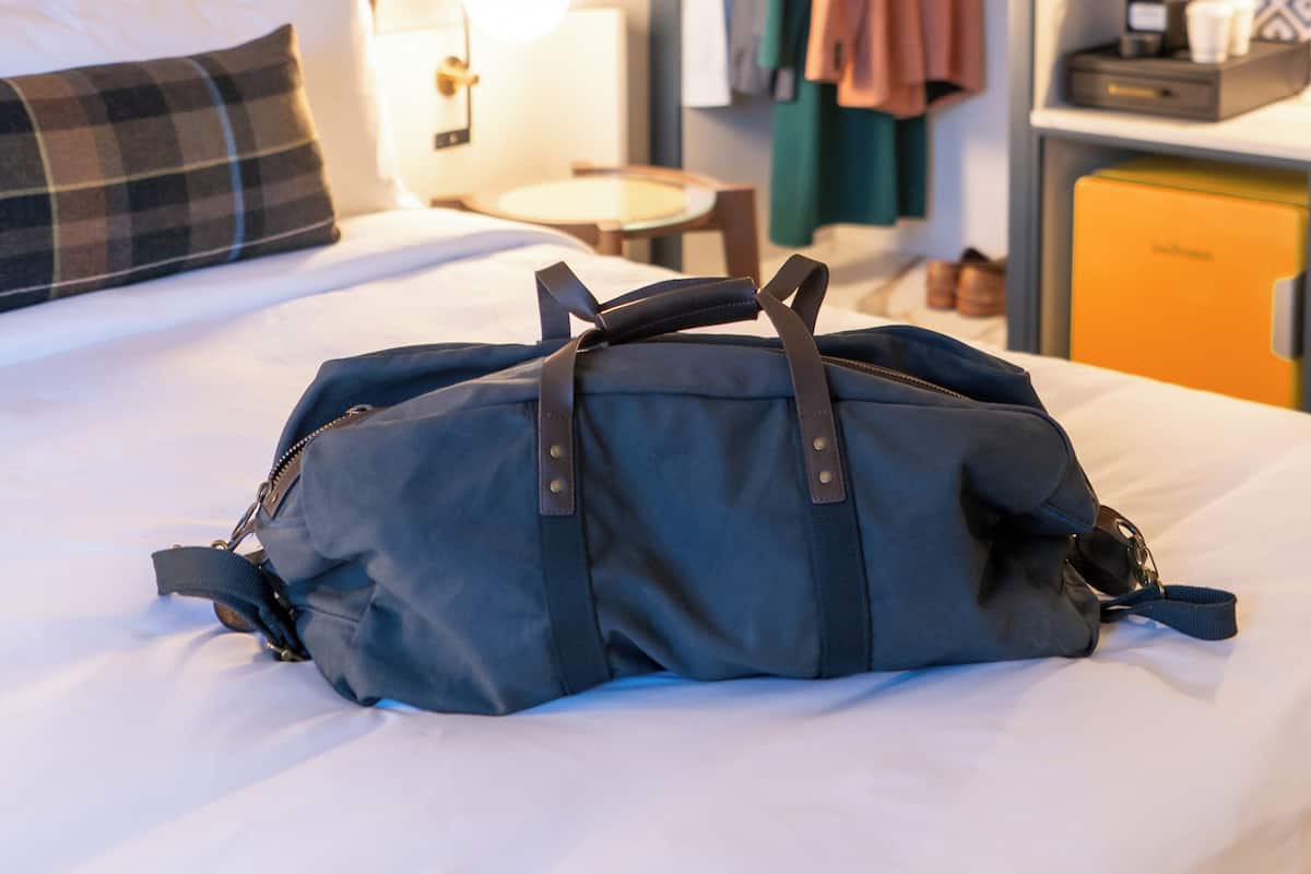 A hotel room with a bed, a bedside lamp, a wardrobe, and a desk with a lamp.