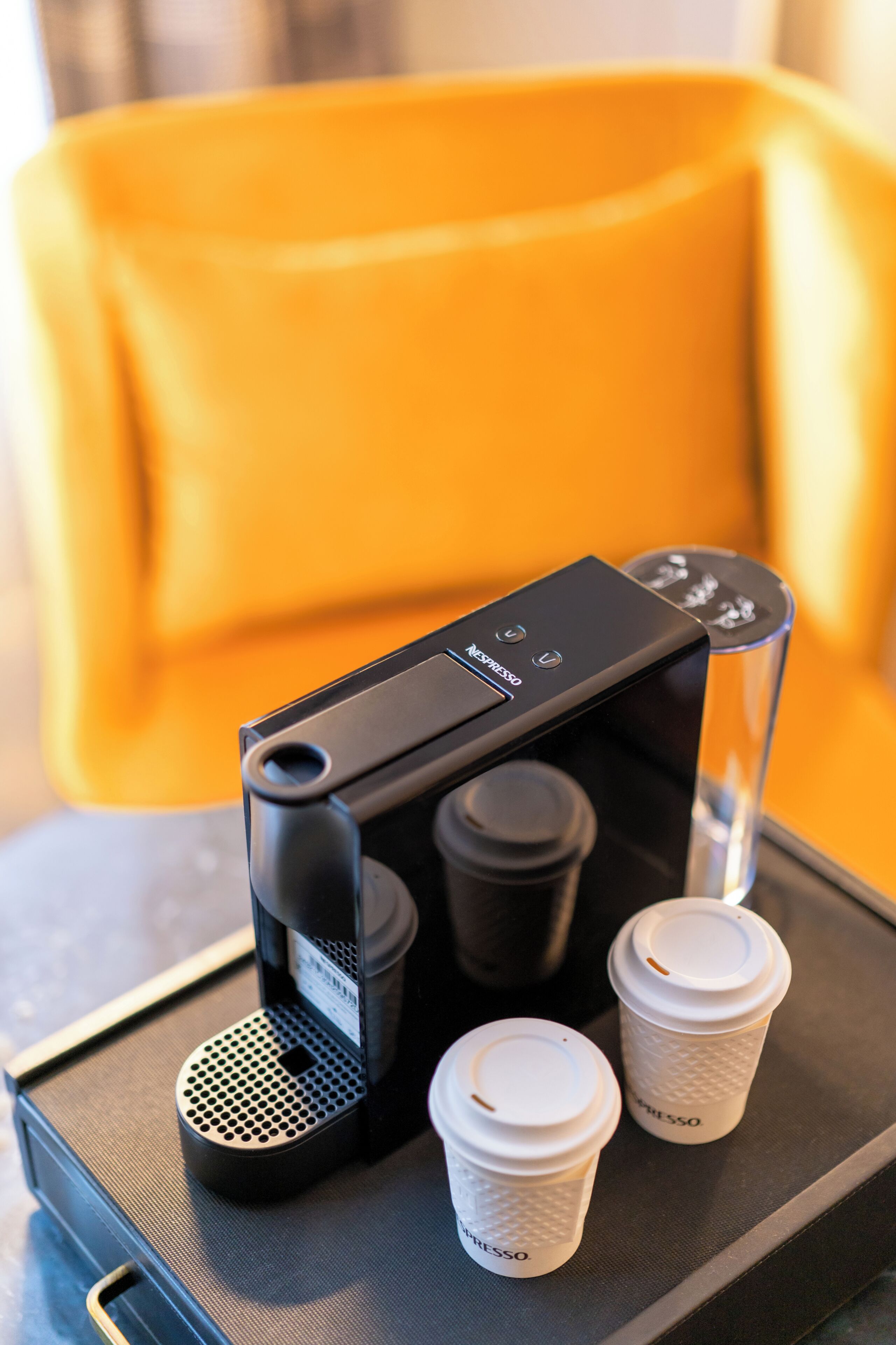 A coffee machine with two disposable cups and a clear glass.