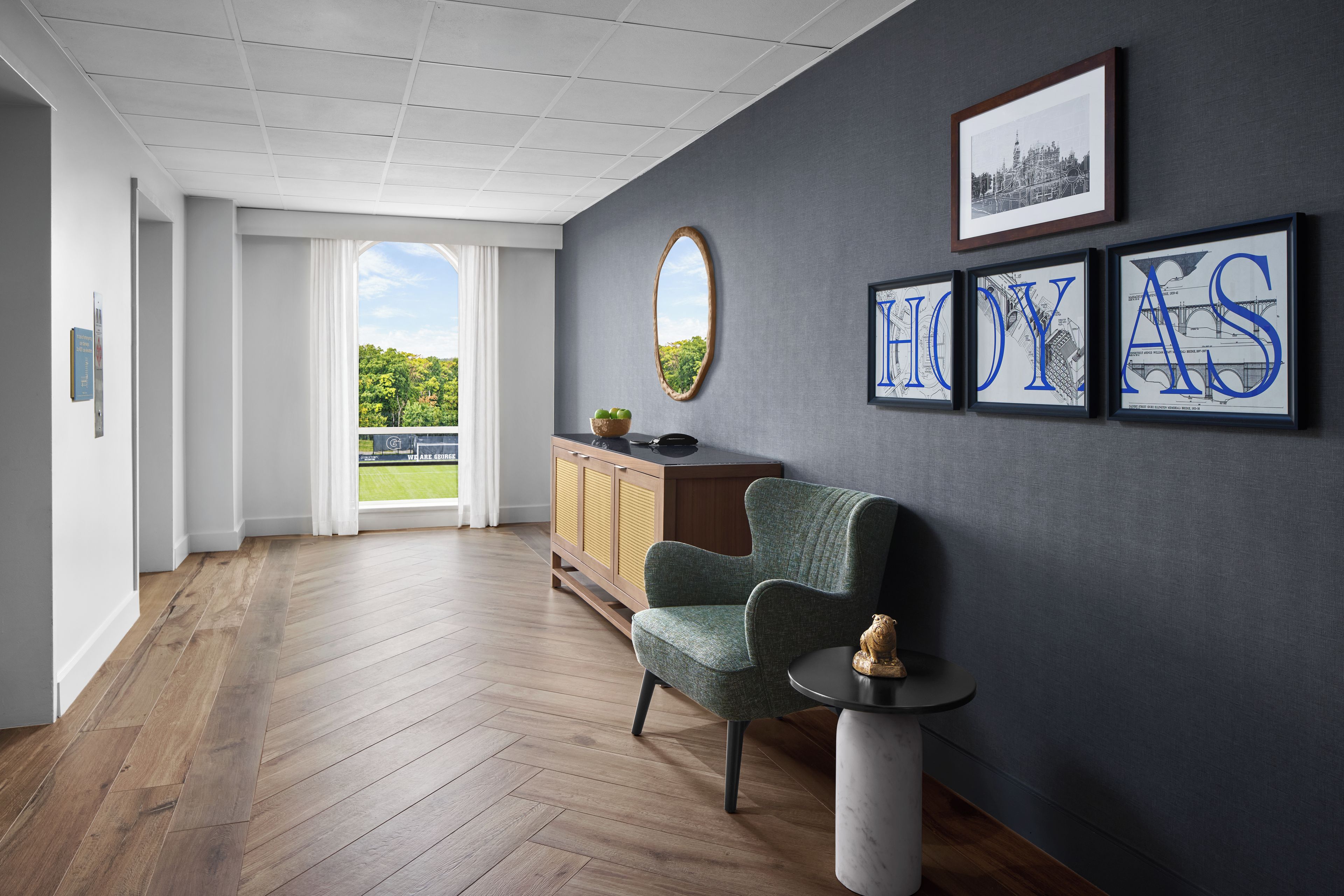 Een modern interieur met een houten vloer, een met groen bekleden stoel, een klein tafeltje en een kast.