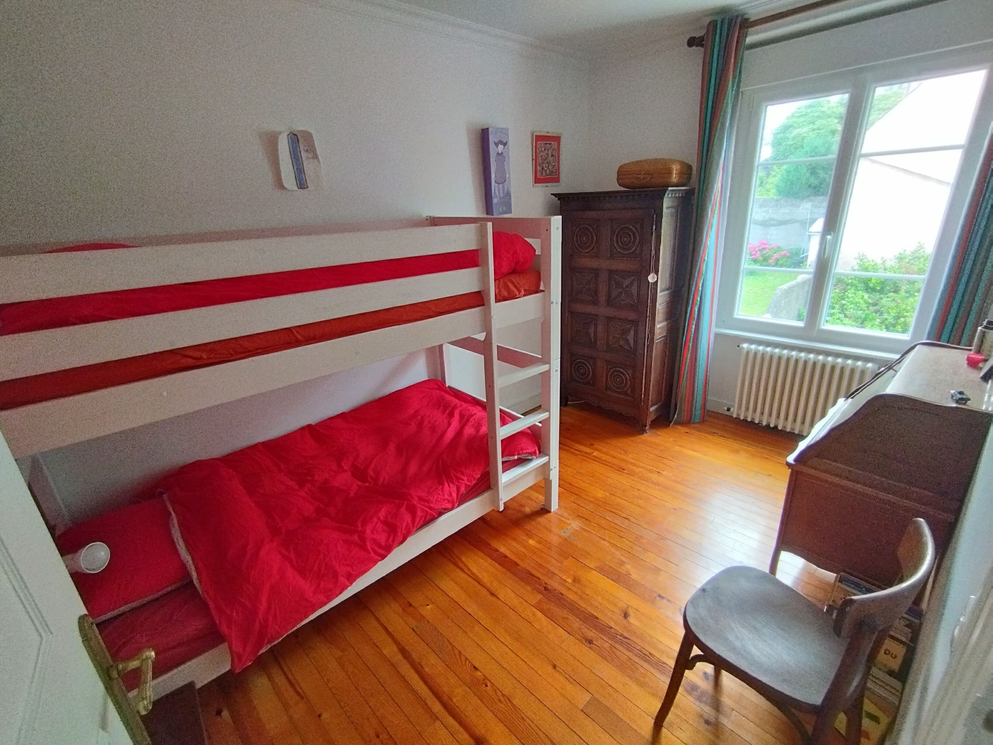 A room with a bunk bed, a desk, a chair, and a radiator.