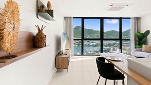 Un soggiorno moderno con zona pranzo, ampie finestre vista città e arredamento minimalista.