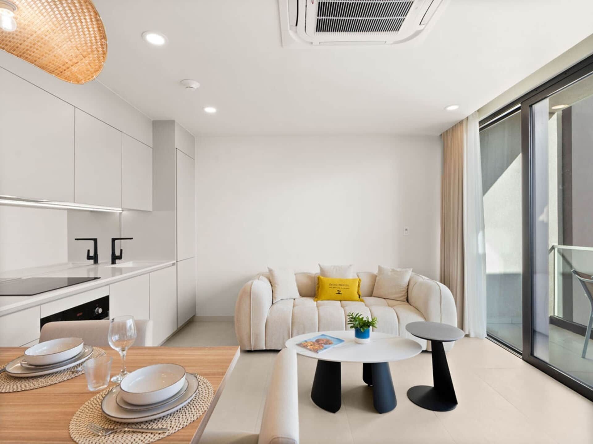 A modern, minimalist living room with a sofa, coffee table, and dining area.