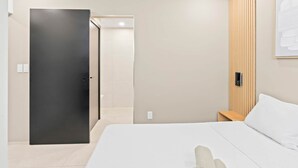 A modern hotel room with a bed, a wooden panel wall, a door, and a framed picture. - D401 Beautiful apartment with a garden lagoon view (Cole Bay)