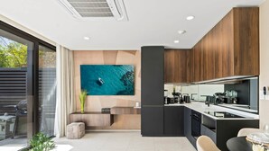 A modern kitchen with a large island, a dining area with a table and chairs, and a living area with a sofa and a plant. - D401 Beautiful apartment with a garden lagoon view (Cole Bay)