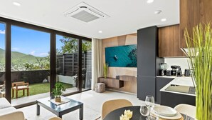 A modern kitchen with a built-in stove, a dining area with a round table, and a large sliding glass door leading to a backyard. - D401 Beautiful apartment with a garden lagoon view (Cole Bay)