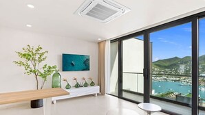Habitación de hotel moderna con un amplio ventanal que ofrece vistas a un puerto deportivo y colinas.