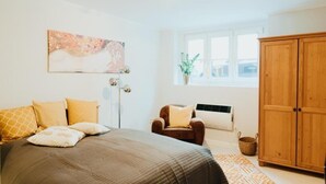 A bedroom with a bed, a chair, a wardrobe, and a window. - Cozy 1-room apartment in central Hamburg Altona (Ottensen)