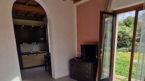A bedroom with two beds, a TV, and a kitchen in the background. - Relax nel Verde 2 - One Bedroom Apartment, Sleeps 3 (Calafuria)