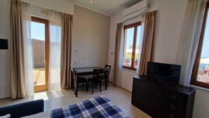 A room with a dining table, chairs, a TV, and a sofa. - Risveglio vista mare 2 (Calafuria)