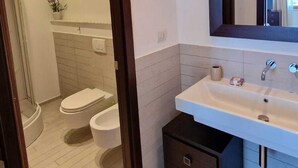 A modern bathroom with a white sink, a large mirror, and a dark wooden cabinet. - Risveglio vista mare 2 (Calafuria)