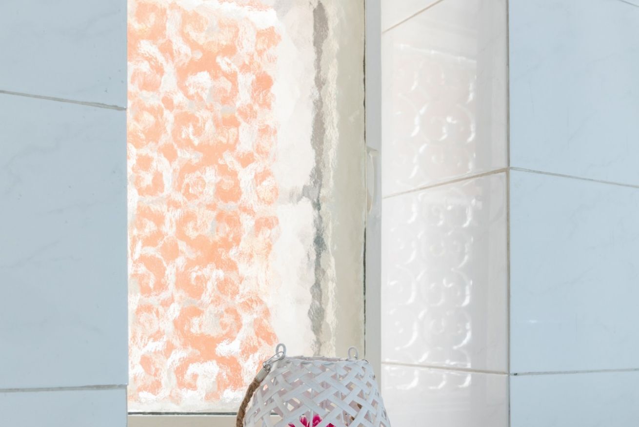A room with a large window, a white wall, and a patterned artwork.