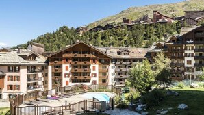 Une station de montagne avec des bâtiments de style chalet, un espace piscine et un paysage montagneux en toile de fond.