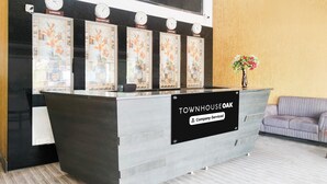A reception desk with clocks indicating different time zones, a sign reading "TOWNHOUSE OAK Company-Serviced", and a sofa in the background.