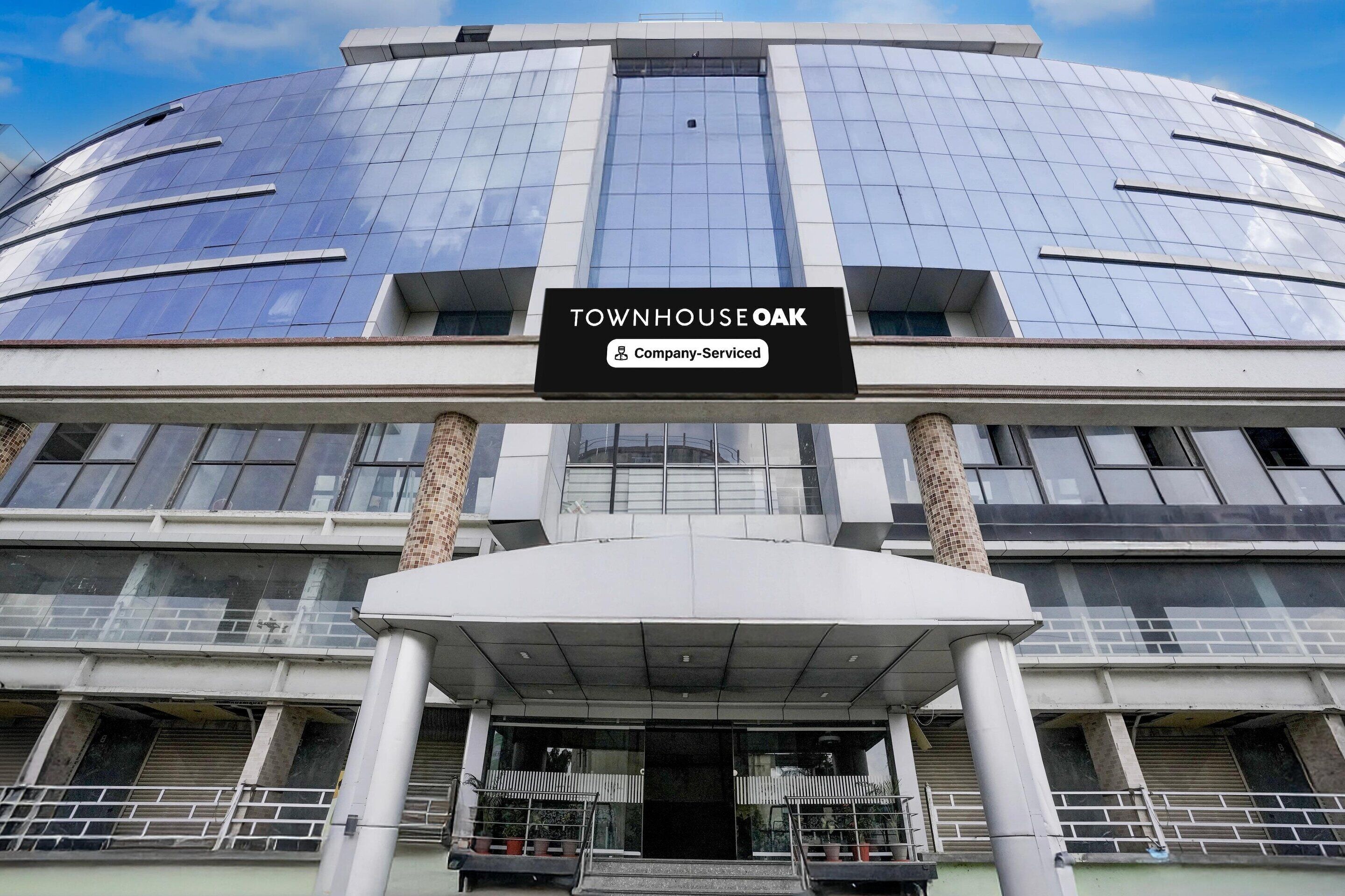 A modern building with a sign reading "Townhouse Oak" and "Company-Served".
