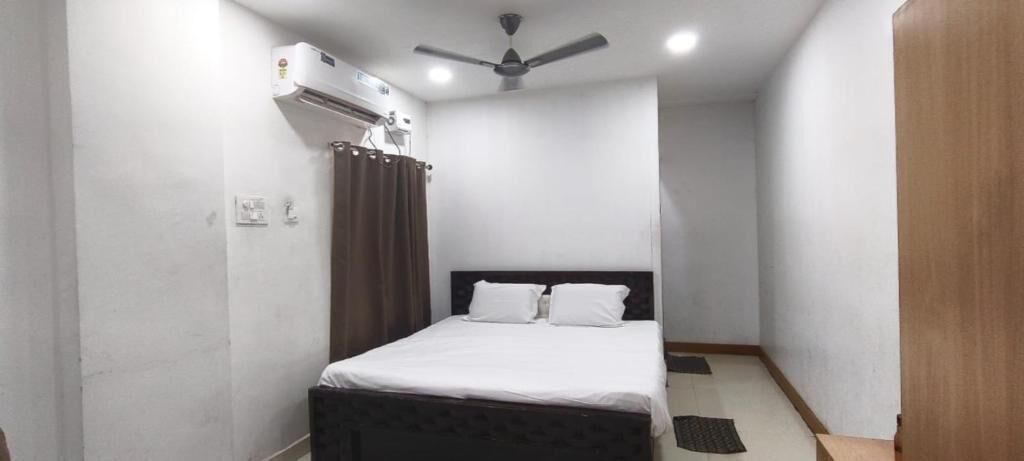 Una camera da letto con un letto, una ventola a soffitto, un condizionatore d'aria e una porta in legno.