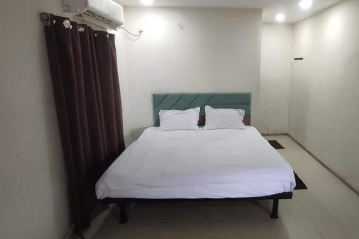 A small, clean room with a single bed, a headboard, and a window with curtains.