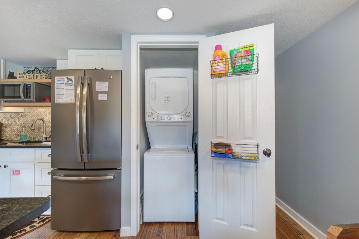 A compact kitchen with a refrigerator, microwave, and a small washing machine.
