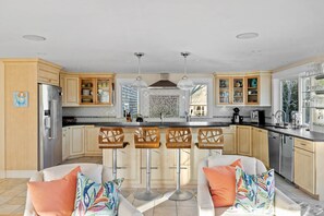 Eine moderne Küche mit Holzschränken, Edelstahlgeräten und einer zentralen Kochinsel mit Barhocker.