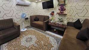 Una sala de estar con paredes decoradas, un televisor de pantalla plana, un sofá, una mesa de centro y una estantería decorativa.