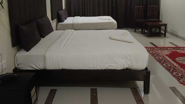 Habitación de hotel con dos camas, un escritorio, una silla, aire acondicionado y un ventilador.