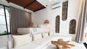 A modern bedroom with a large bed, a sofa, and a unique wooden coffee table. - Villa Beth Eden Uluwatu  (Ungasan)