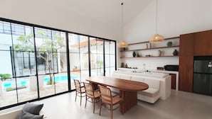 A modern kitchen with a central island, large windows, and a view of an outdoor pool. - Villa Beth Eden Uluwatu  (Ungasan)