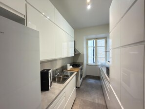 Eine moderne Küche mit weißen Schränken, Edelstahlgeräten und einem Fenster, das für natürliches Licht sorgt.