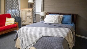 Ein Schlafzimmer mit einem Bett, einem Schminktisch, einem Stuhl und einem Fenster mit Vorhängen.