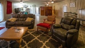 Ein geräumiges Wohnzimmer mit Ledersofas, einem Holztisch und einem gemusterten Teppich.