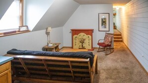 Slaapkamer in loftstijl met een stapelbed, een schommelstoel, een klein tafeltje en een decor kast.