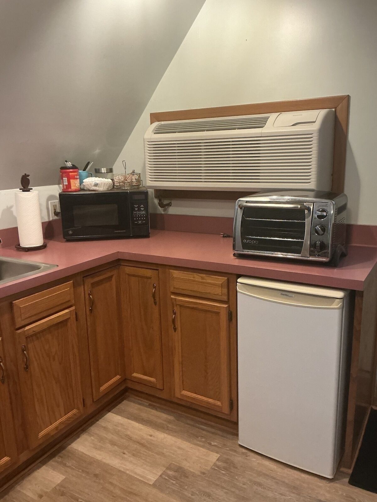 A kitchen with wooden cabinets, a microwave, a toaster, and a refrigerator.