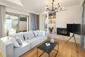 A modern living room with a light grey sofa, a black coffee table, and a TV on a stand. - Infinity - Four Bedroom Villa, Sleeps 8 (Corfu)