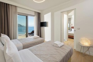 A hotel room with two beds, a TV, a balcony with a chair, and a view of the sea. - Infinity - Four Bedroom Villa, Sleeps 8 (Corfu)