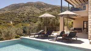 A pool area with lounge chairs and umbrellas, overlooking a mountainous landscape. - Kanelo Villa - Three Bedroom Villa, Sleeps 6 (Makryotika)