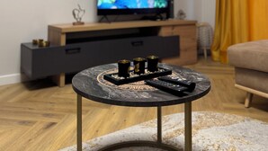 Ett vardagsrum med en tv på ett träställ, ett soffbord med dekorativa föremål och en soffa.