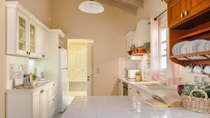 Une cuisine avec des meubles blancs, un grand îlot central doté d’un évier et une porte donnant sur une autre pièce.