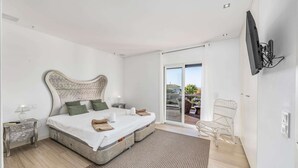 Een slaapkamer met een groot bed, een aan de muur bevestigde televisie en uitzicht op het balkon.