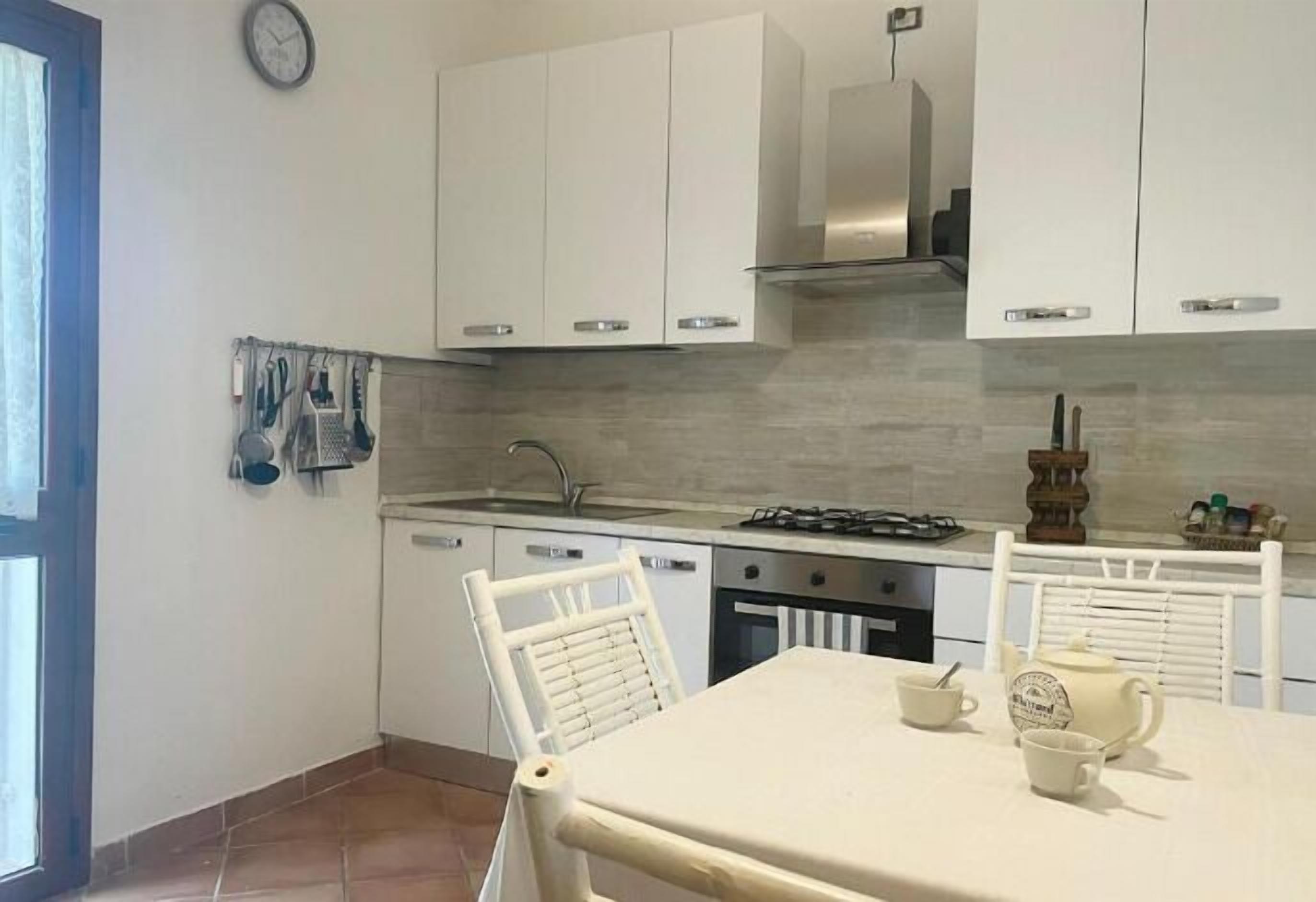 A kitchen with white cabinets, a gas stove, a sink, and a dining table with chairs.