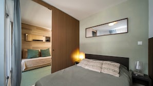 A hotel room with a bed, a nightstand, a mirror, and a wooden wardrobe. - C. du Verdon Ndeg3307 - 2P6 (Allos)