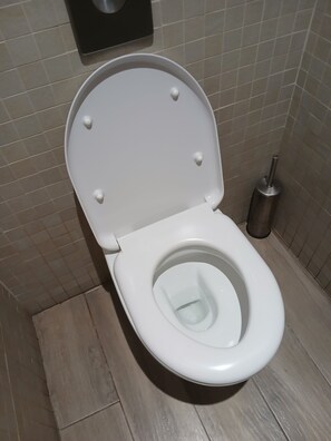 A white toilet with a closed lid, a flush handle, and a toilet brush to the right. - Superb accommodation (La Cala del Moral)