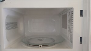 A white microwave with a glass turntable, a control panel, and ventilation grills. - Superb accommodation (La Cala del Moral)